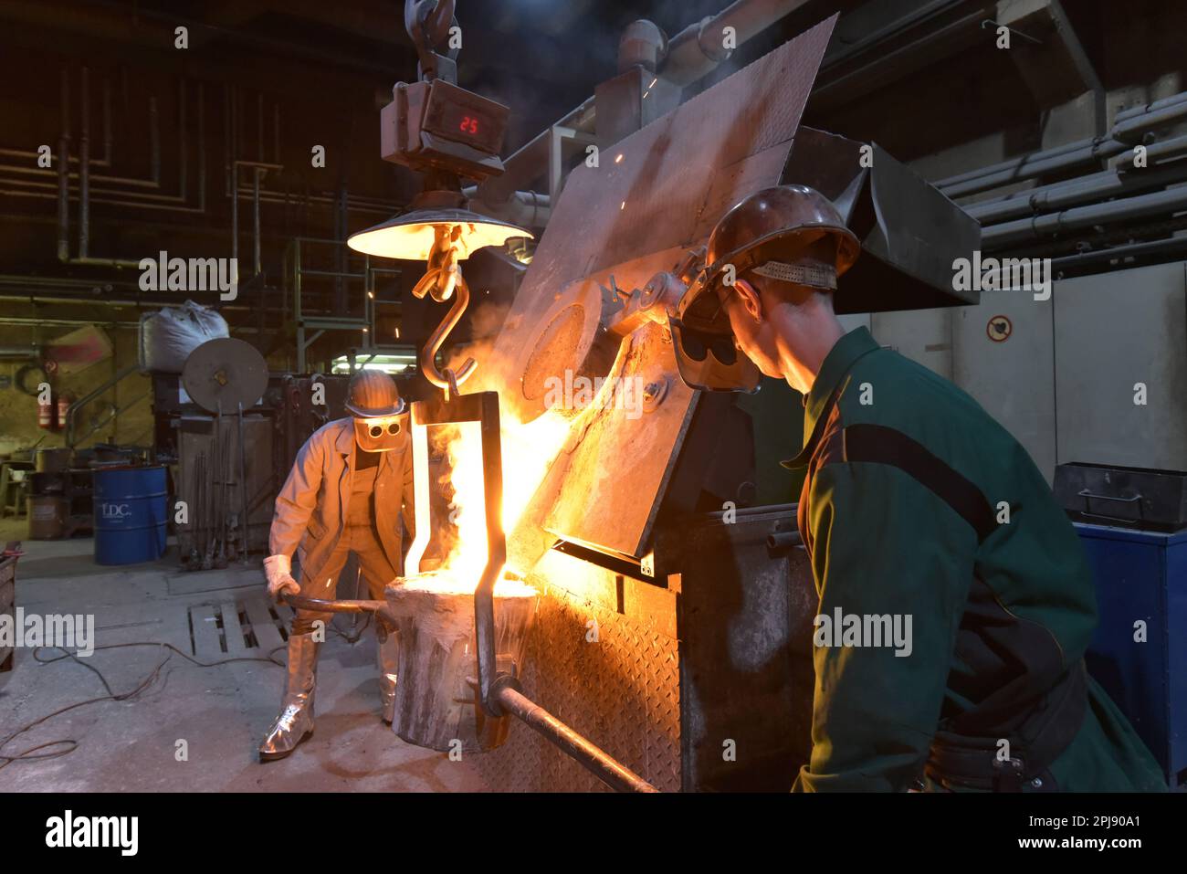 I lavoratori in un getto di fonderia di un pezzo di metallo - Sicurezza sul lavoro e il lavoro di squadra Foto Stock