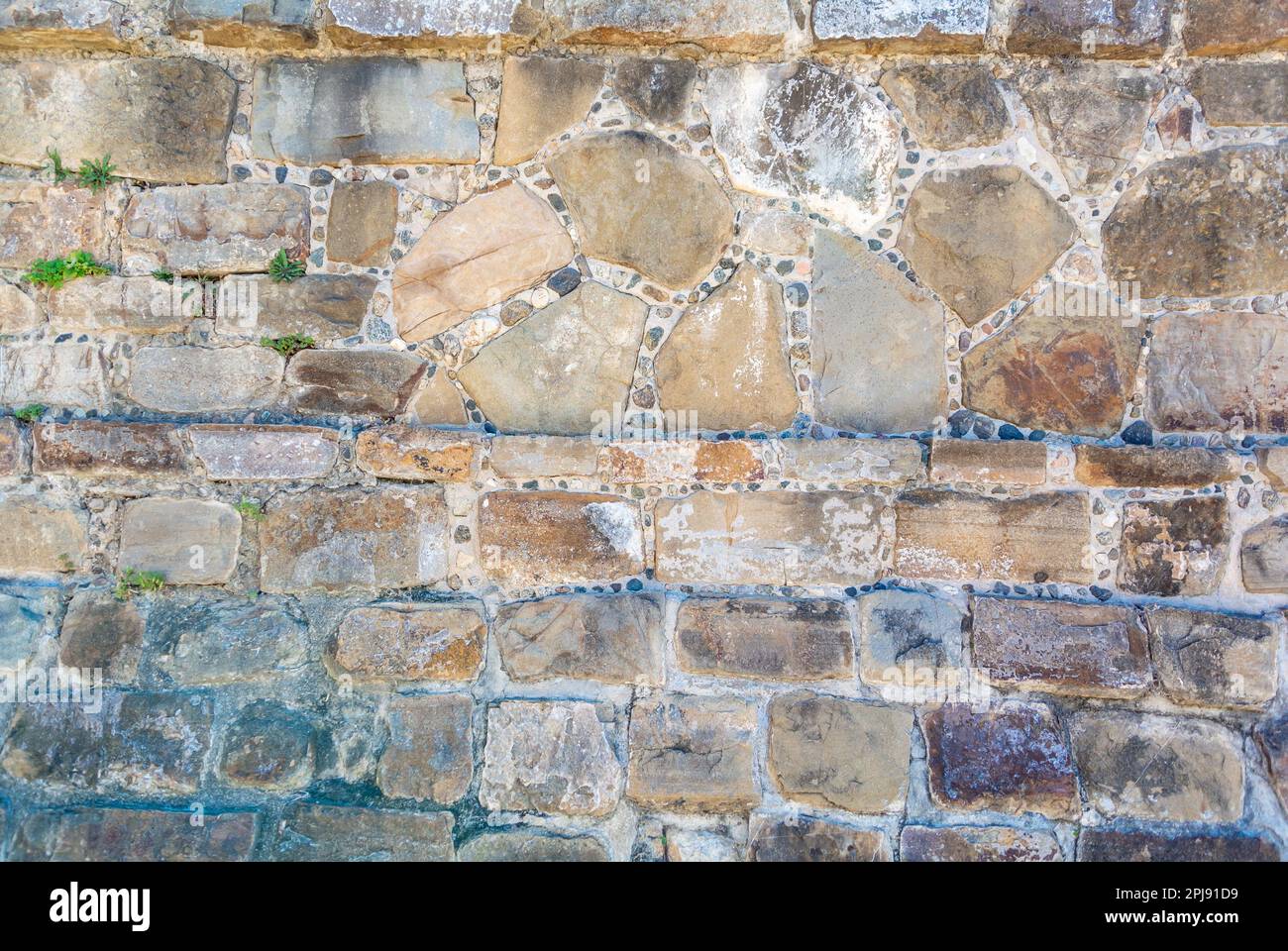 Vecchio muro di pietra fatto di rocce e cemento Foto Stock