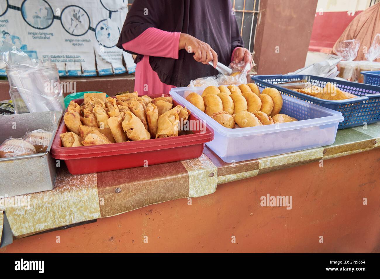 Una vista laterale di una donna non identificata che vende cibo di strada Indonesiano. un tipo di takjil fritto alla perfezione. Ramadan 2023 Foto Stock