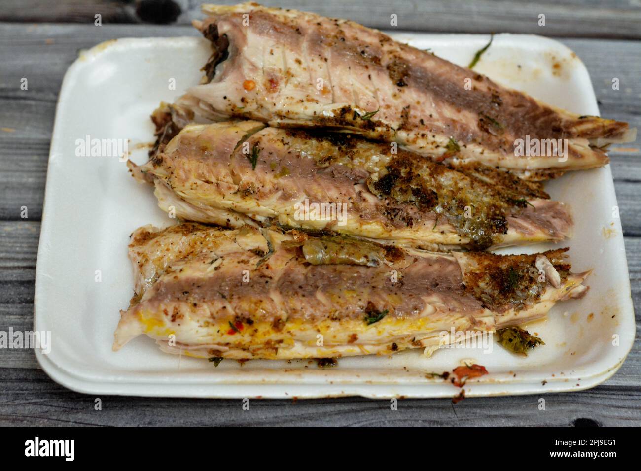 Focus selettivo di pesci triglia alla griglia con grano gran, puliti e serviti in piatto bianco usa e getta, cucina di pesce di triglia alla griglia egiziana, de Foto Stock