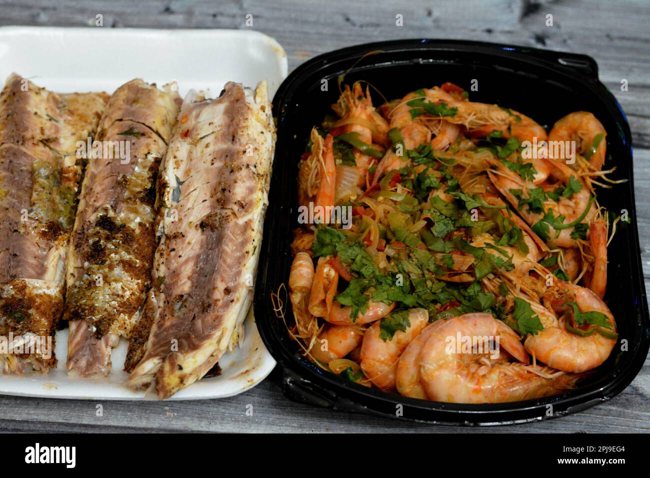 Cucina a base di pesce di gamberi bolliti, aglio, limone, prezzemolo, pepe, cipolla e pomodoro e triglie grigliate al carbone con prezzemolo e t Foto Stock