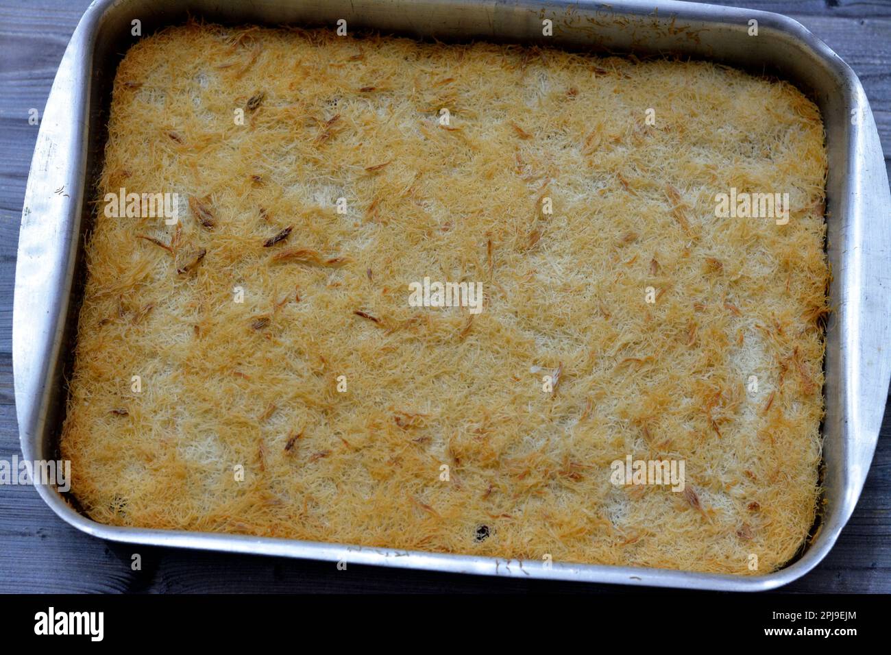 Un tradizionale dessert mediorientale Knafeh Konafa fatto con kataifi di pasta filata, imbevuto in uno sciroppo di miele di zucchero dolce, stratificato con formaggio, o coagulato Foto Stock