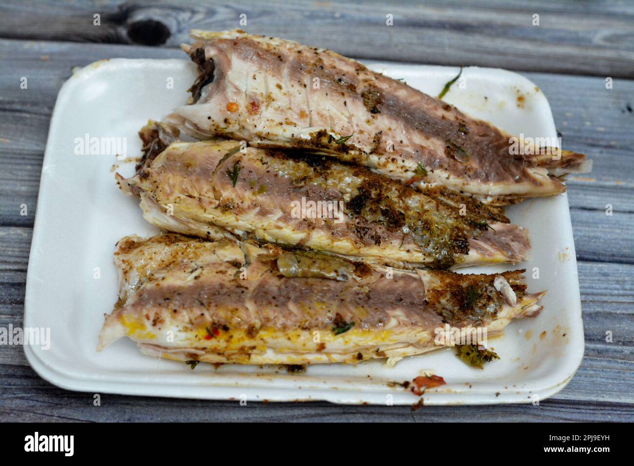 Focus selettivo di pesci triglia alla griglia con grano gran, puliti e serviti in piatto bianco usa e getta, cucina di pesce di triglia alla griglia egiziana, de Foto Stock