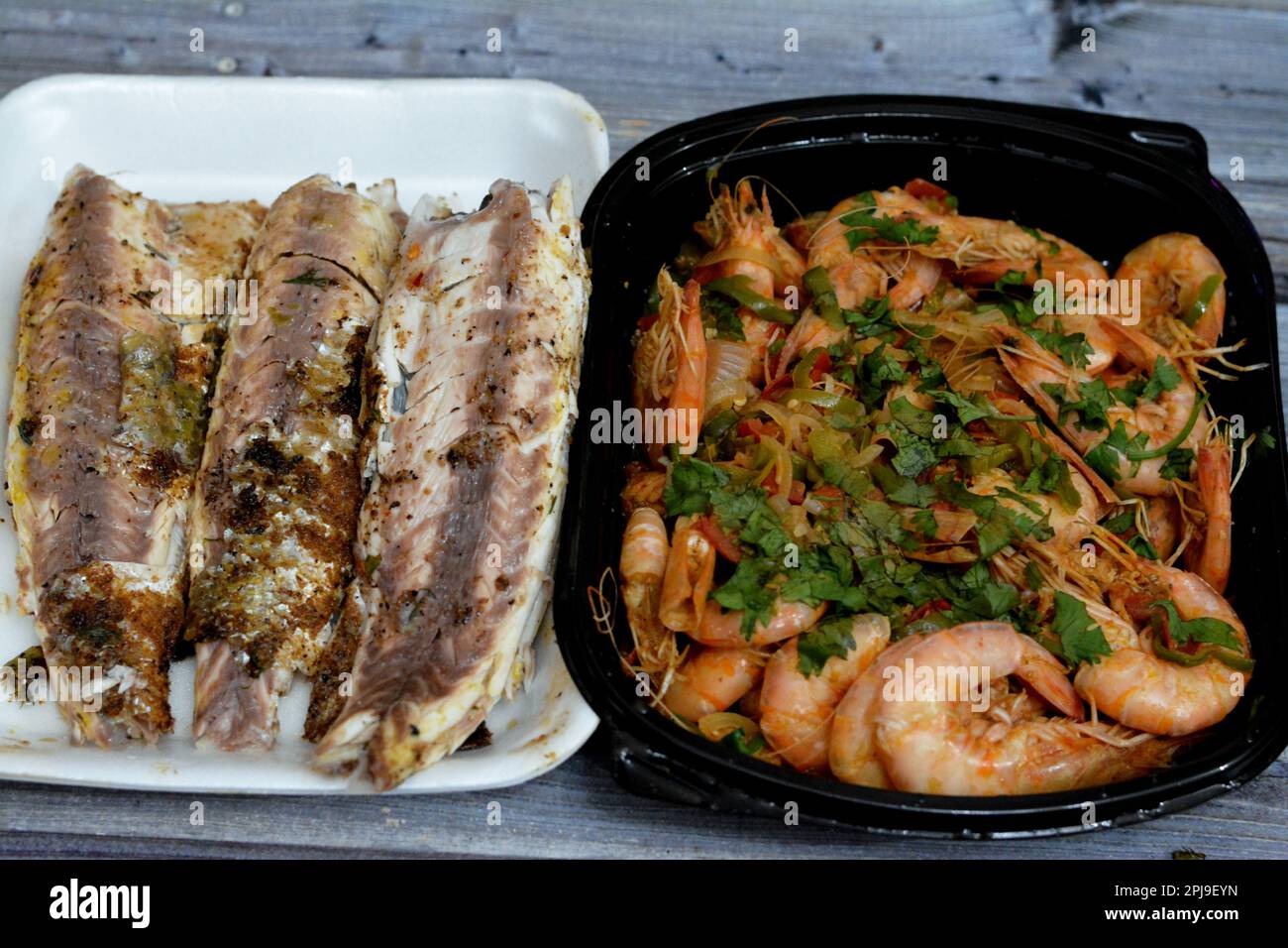 Cucina a base di pesce di gamberi bolliti, aglio, limone, prezzemolo, pepe, cipolla e pomodoro e triglie grigliate al carbone con prezzemolo e t Foto Stock