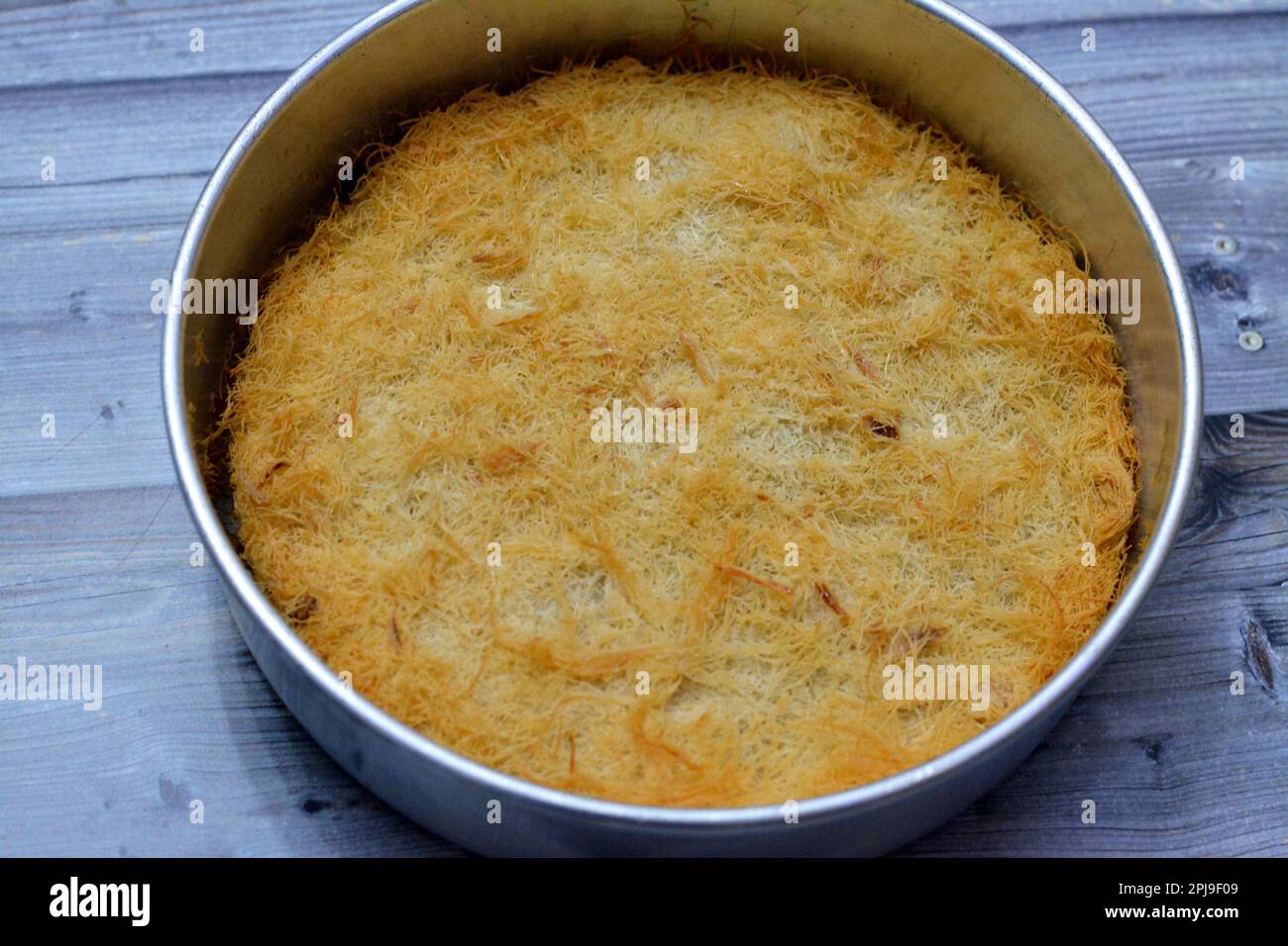 Un tradizionale dessert mediorientale Knafeh Konafa fatto con kataifi di pasta filata, imbevuto in uno sciroppo di miele di zucchero dolce, stratificato con formaggio, o coagulato Foto Stock
