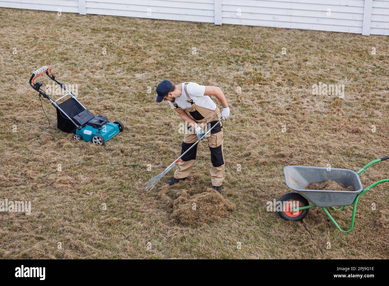 Prato scarificatore con rastrello e scarificatore, uomo giardiniere  scarifica il prato e la rimozione di erba vecchia Foto stock - Alamy