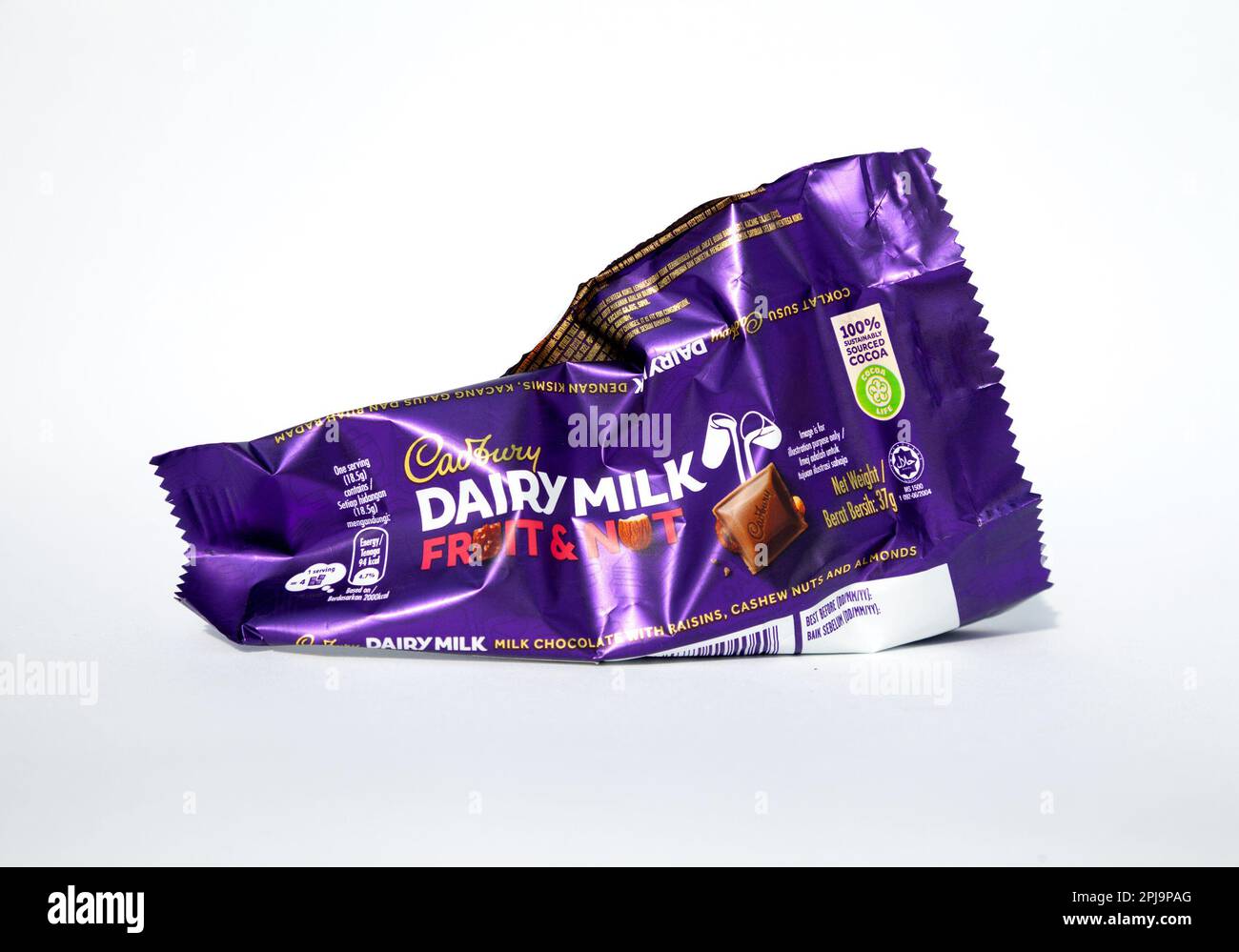 Ho Chi Minh City, Vietnam - 28 marzo 2023: Cadbury latte latte latte latte frutta e noci barra di cioccolato vuoto sbriciolato involucro isolato su bianco. Popolare purple di caramelle Foto Stock