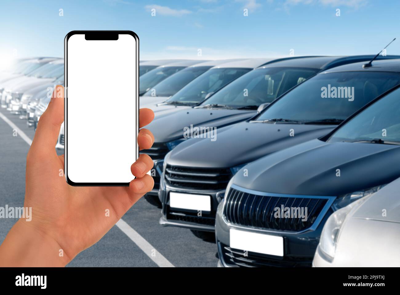 Mano con il telefono su uno sfondo di file di automobili. Vendite di automobili. Foto Stock