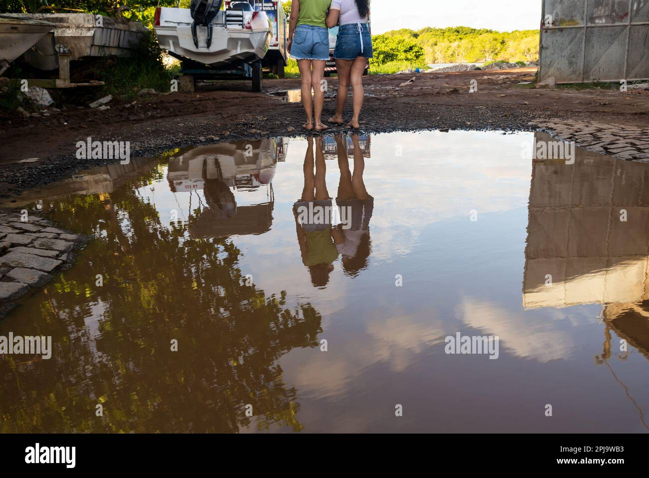 Due donne si sono riflesse nella pozza d'acqua, abbracciando. Città di Valenca, Bahia. Foto Stock