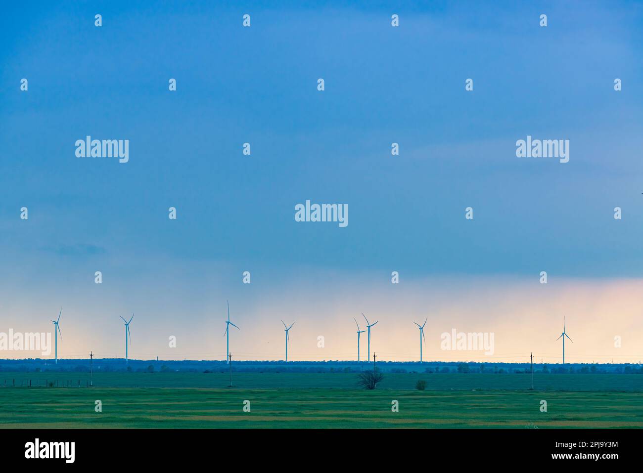 Paesaggio minimalista con turbine eoliche e campo di grano verde sotto il cielo piovoso Foto Stock