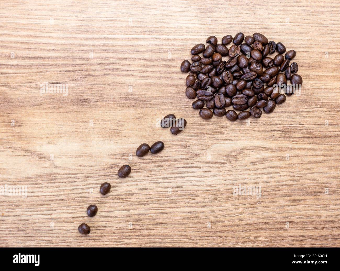 Concetto, pensiero o pensare al caffè. Bolla di pensiero composta da chicchi di caffè tostati su un asse di legno. Foto Stock