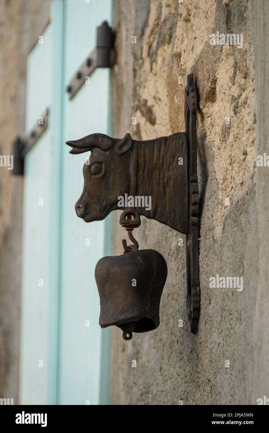 Campana rustica a forma di mucca montata su un muro di legno in una fattoria rurale durante il giorno, Auvergne, Francia Foto Stock