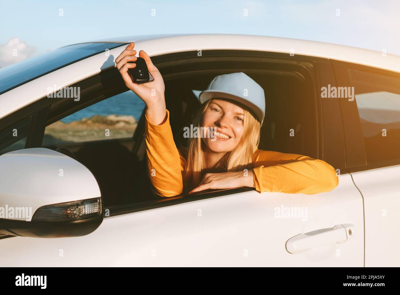 Autista donna che viaggia in auto a noleggio mostrando le chiavi nella finestra aperta. Viaggio su strada vacanze trasporto concetto di assicurazione Foto Stock