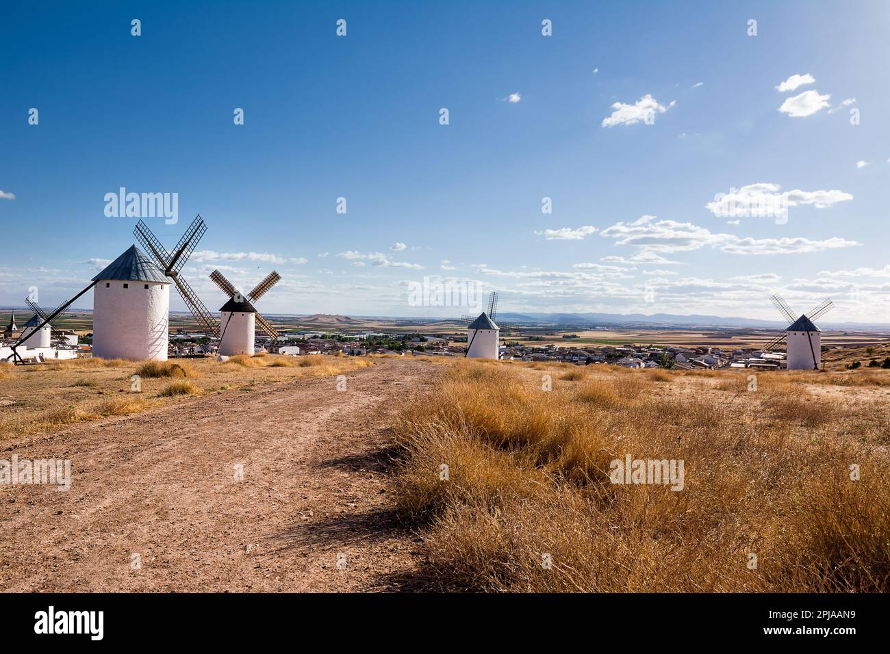Campo secco con antichi mulini a vento e sotto il villaggio di campo de Criptana, Spagna, definito in Cervantes 'Don Chisciotte 'i Giganti' Foto Stock