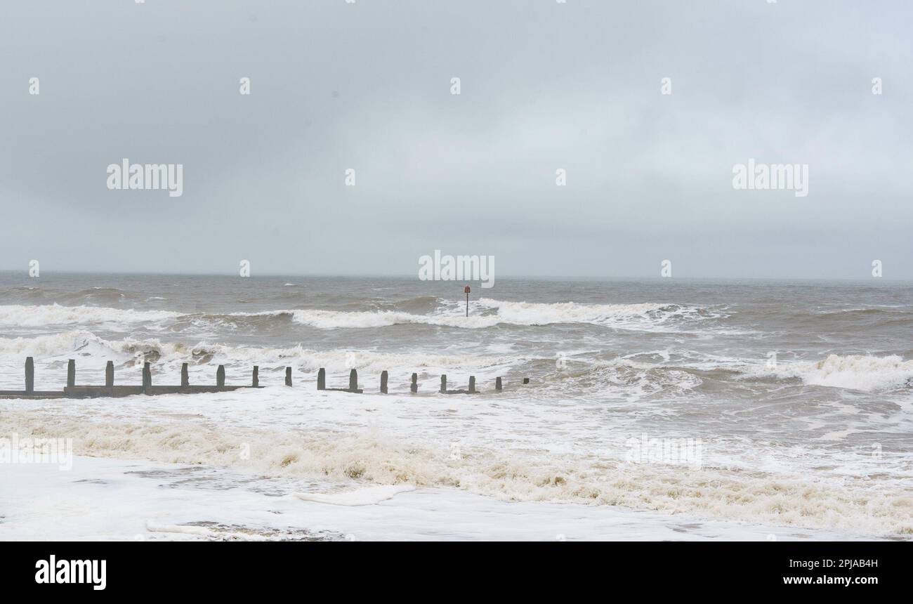 Aprile 1st 2023. Hornsea, E.Yorkshire. Un pomeriggio arrugginito e misteriosa, con la pioggia visibile sul Mare del Nord. NELLA FOTO: Onde che si infrangono sul lungomare. Bridget Catterall/AlamyLiveNews Foto Stock