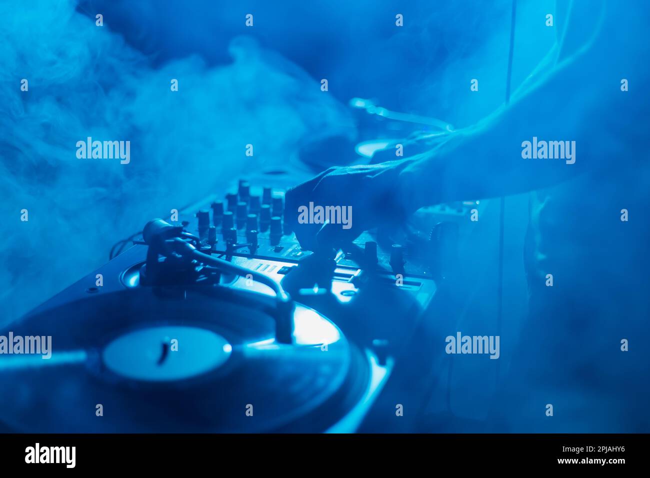 Silhouette di un DJ club che mescola musica in fumo sul palco. Il jokey professionale del disco suona sul partito techno Foto Stock