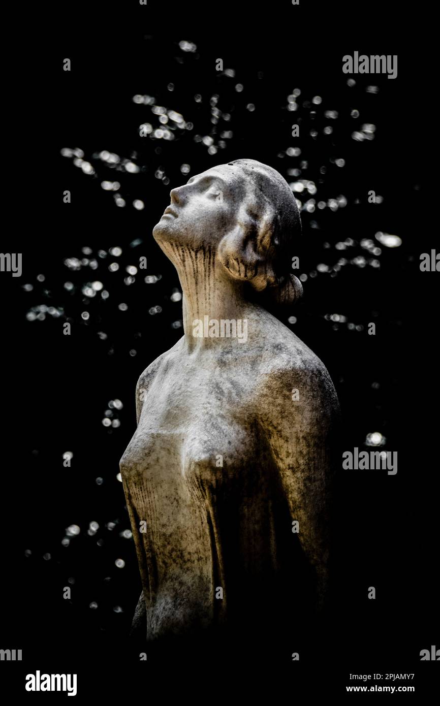 Una statua commemorativa di fronte alle foglie del Cimitero Monumentale di Milano Foto Stock