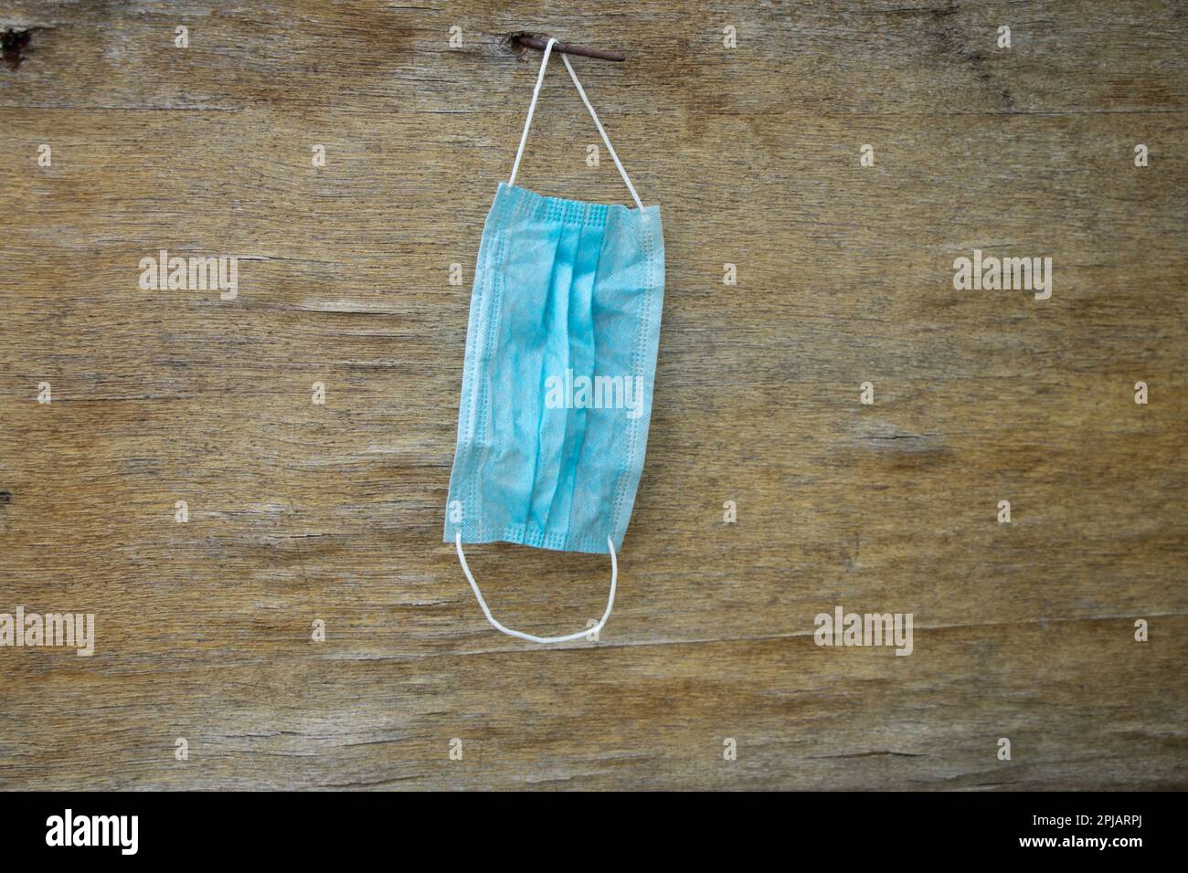 maschera medica appesa ad una vecchia recinzione di legno Foto Stock