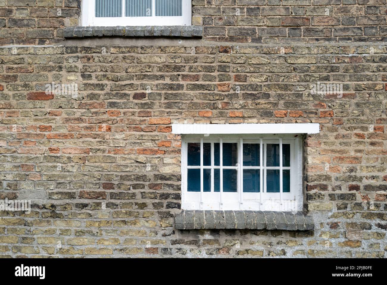 Vista astratta di una vecchia prigione di polizia che mostra le barre di ferro. Il muro di mattoni si affaccia su un vicino cimitero inglese Foto Stock