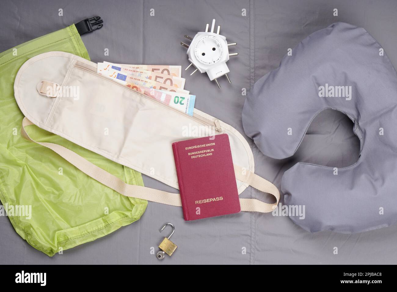A tema Laico piatta con cuscino viaggio, cinghia di denaro, passaporto tedesco, international travel adapter e lucchetto Foto Stock