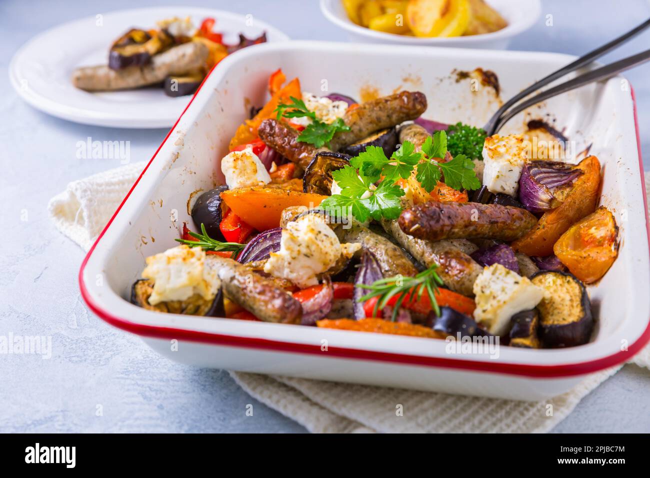 Salsicce arrosto con verdure e formaggio feta in casseruola Foto Stock