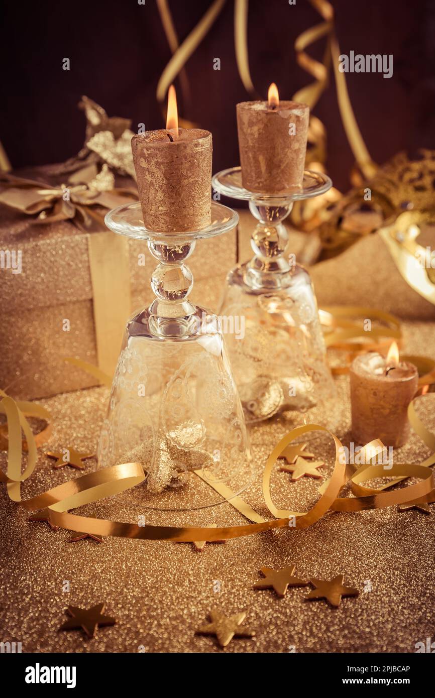 Decorazione domestica con candele e scatola del regalo in tonalità dorate su fondo dorato. Capodanno, festa o festa di compleanno Foto Stock