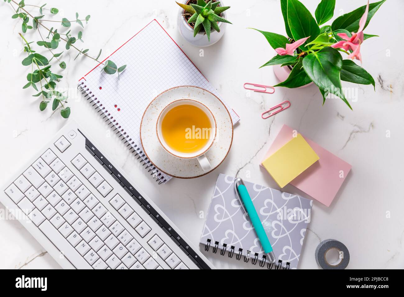 Scrivania da lavoro a casa piatta con dispositivo di comunicazione con tazza di tè e strumenti di scrittura. Femminile business mockup, copyspace, sfondo bianco Foto Stock