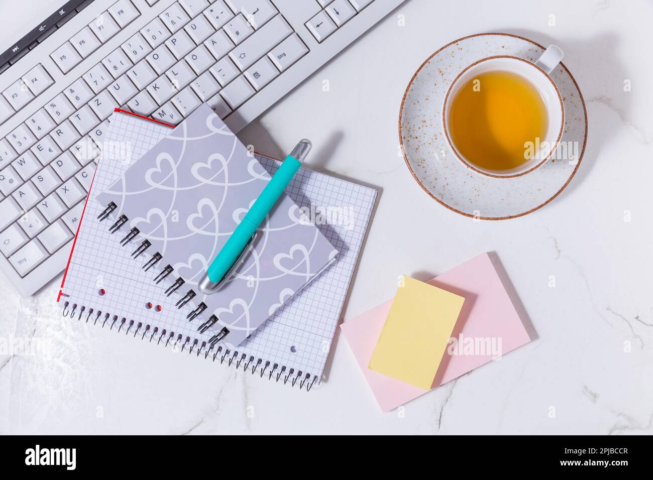 Scrivania da lavoro a casa piatta con dispositivo di comunicazione con tazza di tè e strumenti di scrittura. Femminile business mockup, copyspace, sfondo bianco Foto Stock