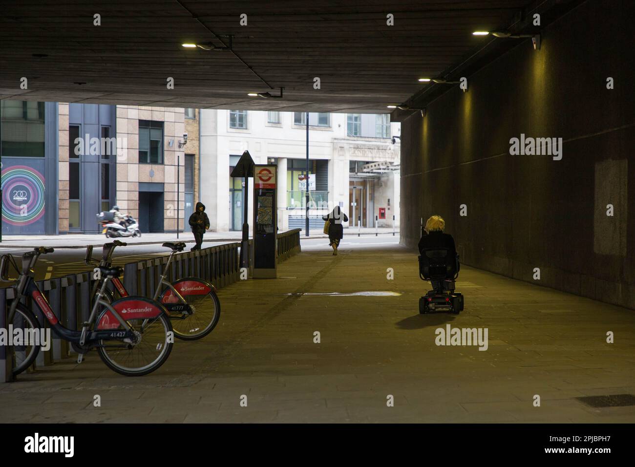 Lady su uno scooter per la mobilità in un sottopassaggio urbano a Londra Foto Stock