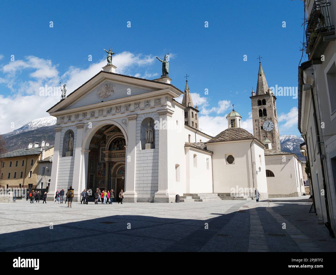 Persone fuori dall'ingresso della Cattedrale di Santa Maria Assunta nella città di Aosta, Valle d'Aosta, Italia. Ombra di primo piano. Foto Stock