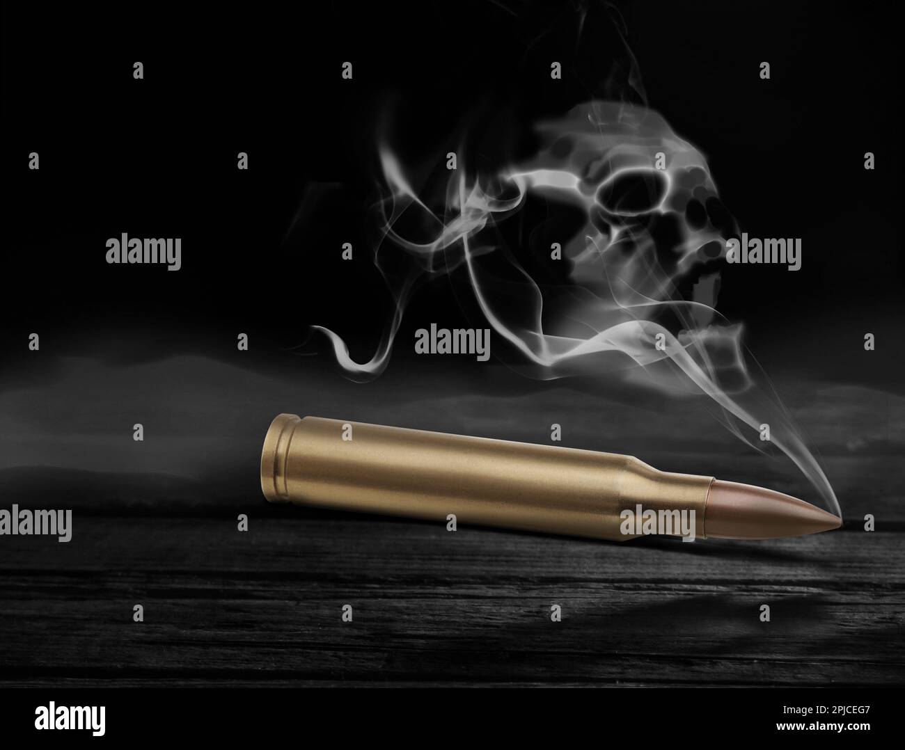 Proiettile con fumo a forma di cranio su tavolo di legno nero Foto Stock