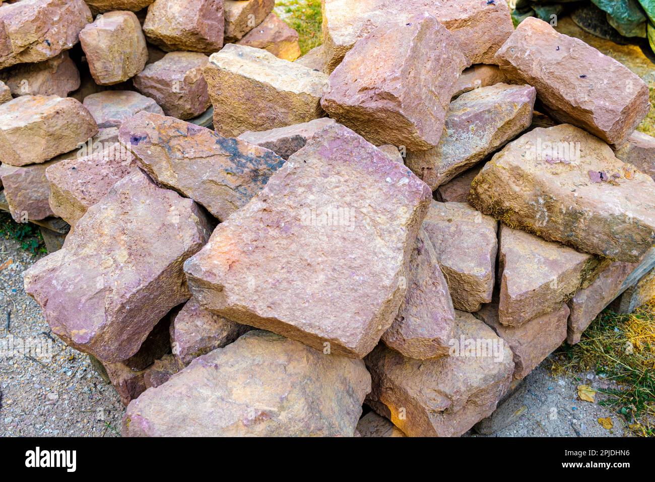 Un mucchio di vecchie pietre arenarie lavorate su un cantiere per il restauro di un vecchio muro Foto Stock