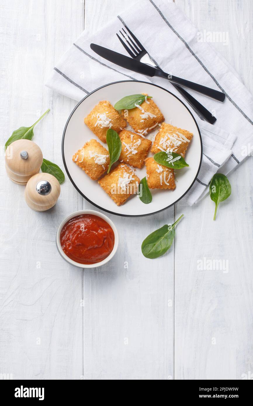 Ravioli fritti fatti in casa con salsa Marinara e parmigiano sul tavolo di legno. Vista verticale dall'alto Foto Stock