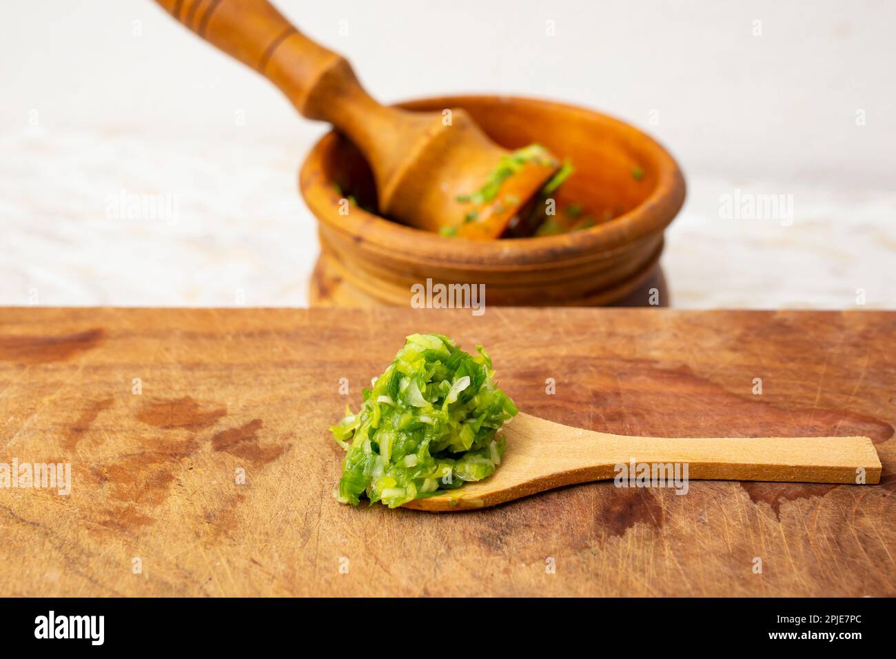 Pasta fresca e verde di foglie d'aglio chiamato mujdei in cucina rumena, fatta in un mortaio di legno pestello, vista laterale primo piano Foto Stock