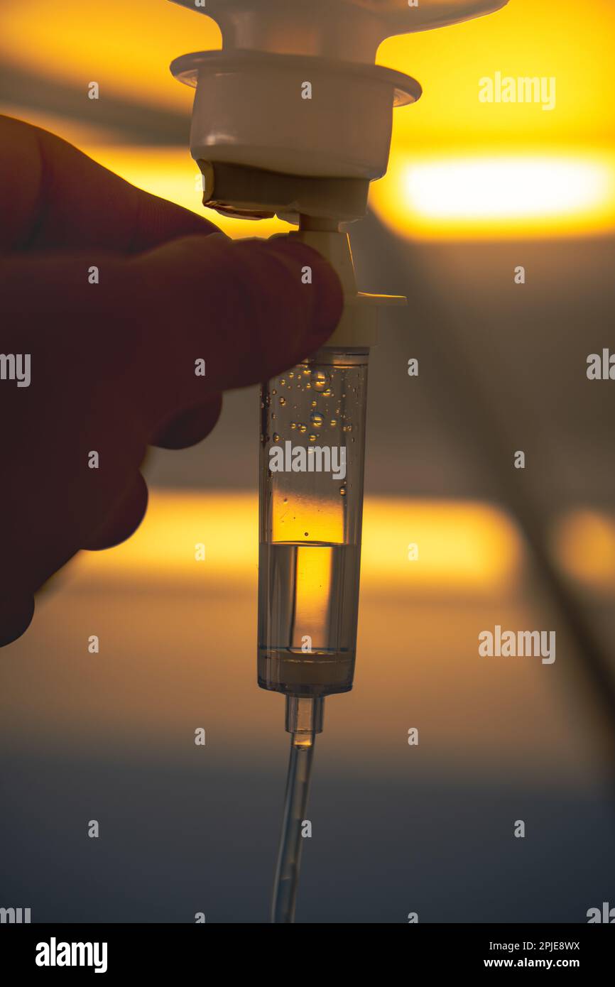 Infermiera che tiene la mano e che controlla il contagocce di chemioterapia e la cura di salute della vitamina all'infusione endovenosa di notte. Foto Stock