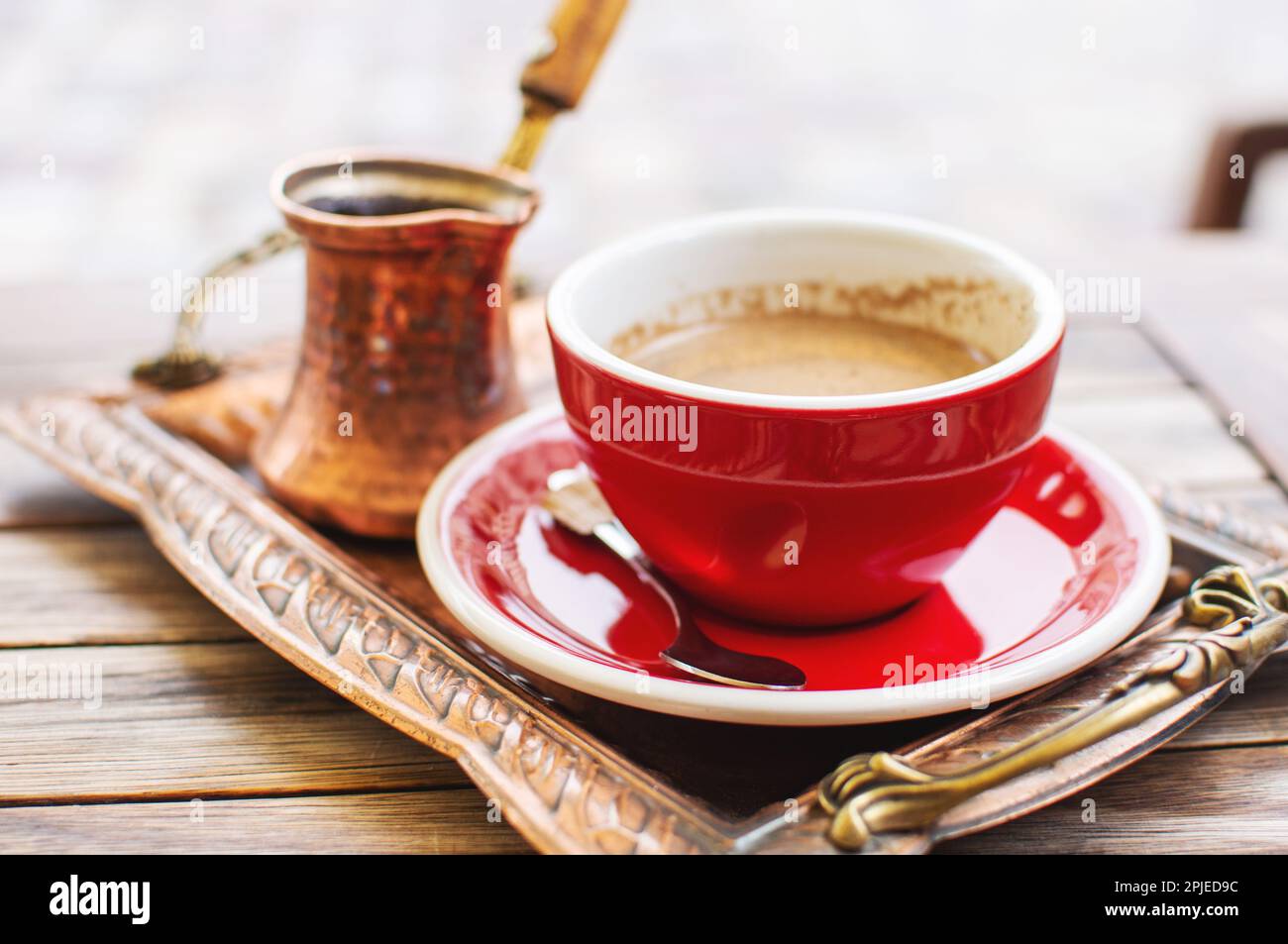 Il tradizionale caffè turco viene servito in una tazza e una caffettiera metallica sulla terrazza di un caffè di strada. Foto Stock