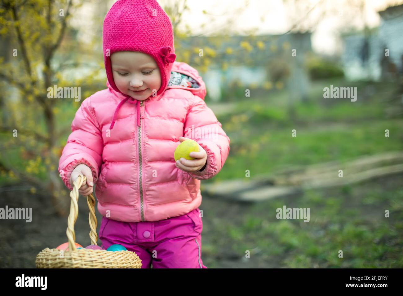 Il bambino raccoglie le uova di Pasqua colorate nel cestino. Concetto di caccia all'uovo di Pasqua. Foto Stock