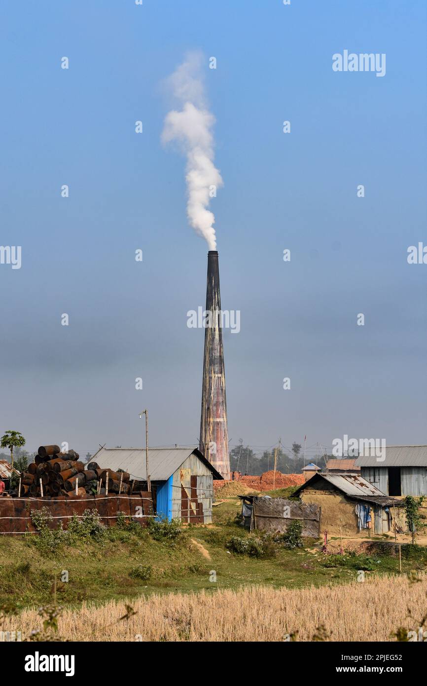 Un camino di una fabbrica di mattoni a Tripura causando inquinamento con il cielo blu . Foto Stock