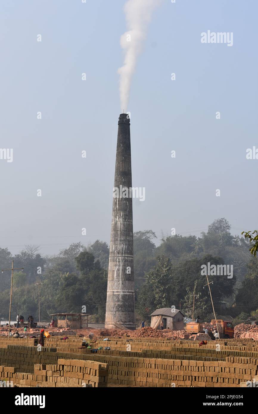 Un camino di una fabbrica di mattoni a Tripura causando inquinamento con il cielo blu . Foto Stock