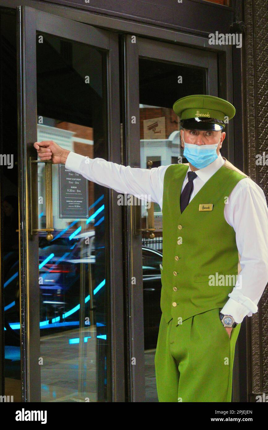 Londra, Inghilterra 20 agosto 2021: Famoso Doorman di Harrod con maschera facciale e caratteristica uniforme verde brillante con bottoni d'oro. Foto Stock