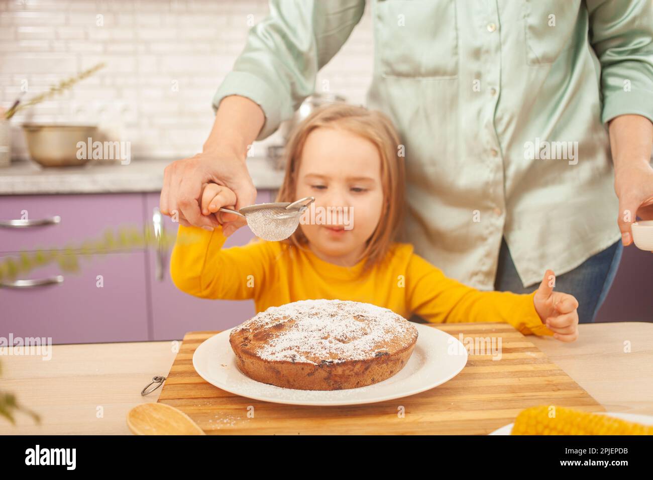 Ritratto di bambina di tre anni, cucina, torta, dabbling, divertente. zucchero a velo Foto Stock