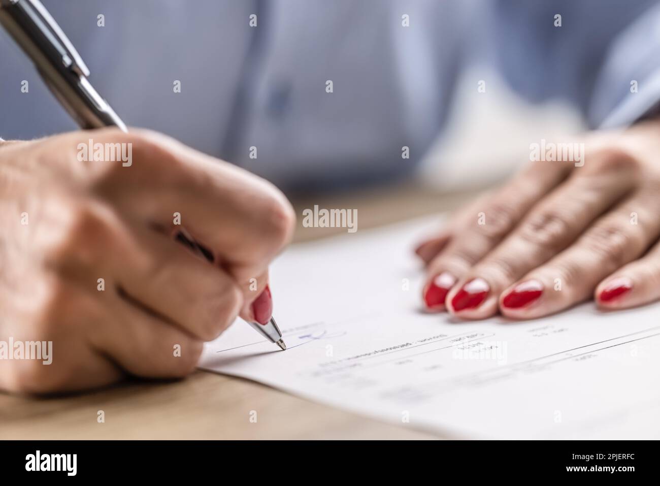 Dettaglio delle mani femminili che firmano un contratto cartaceo o un accordo con una penna. Foto Stock