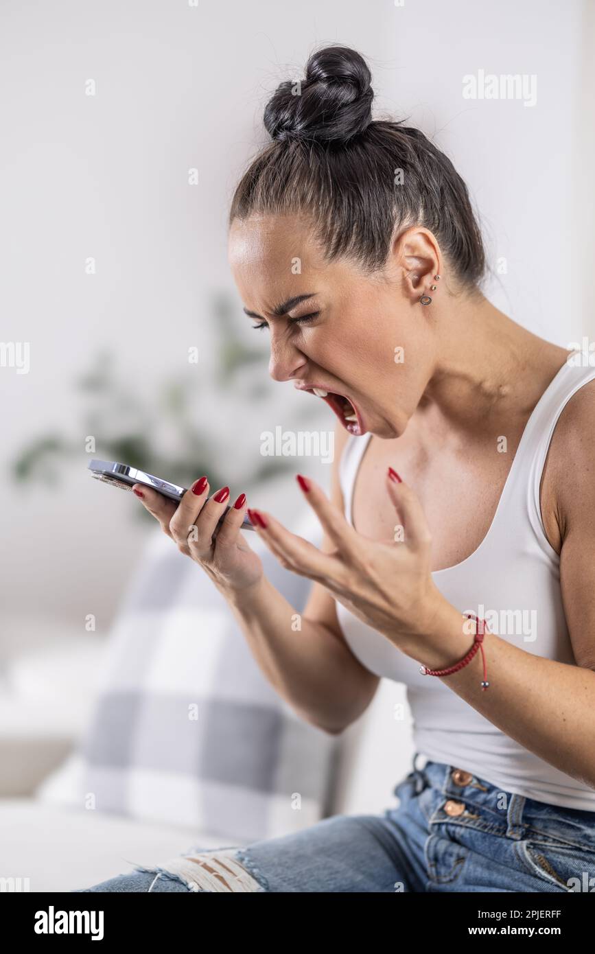 Donna sconvolta grida con la bocca aperta nel telefono su altoparlante mostrando forte gesto della mano. Foto Stock
