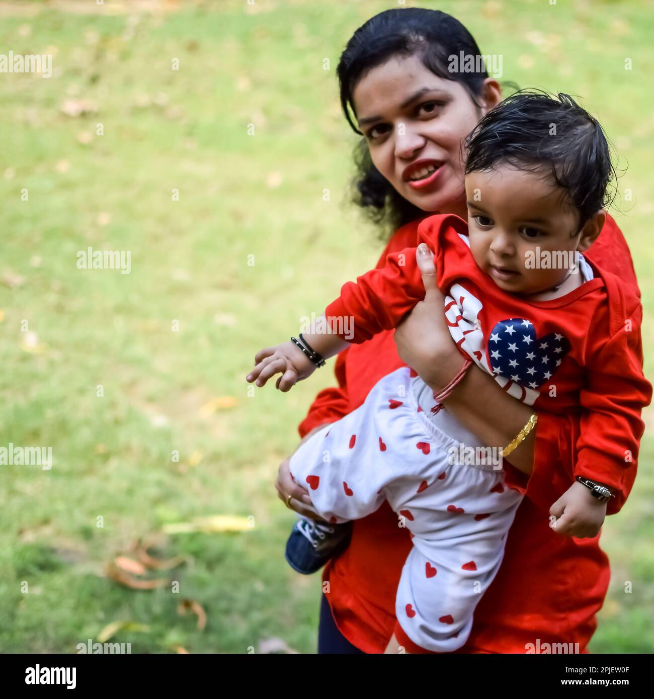 Mamma amorevole che porta il suo bambino al parco sociale. Ritratto luminoso di mamma felice che tiene il bambino nelle sue mani. Madre abbraccia il suo piccolo figlio di 9 mesi. Foto Stock