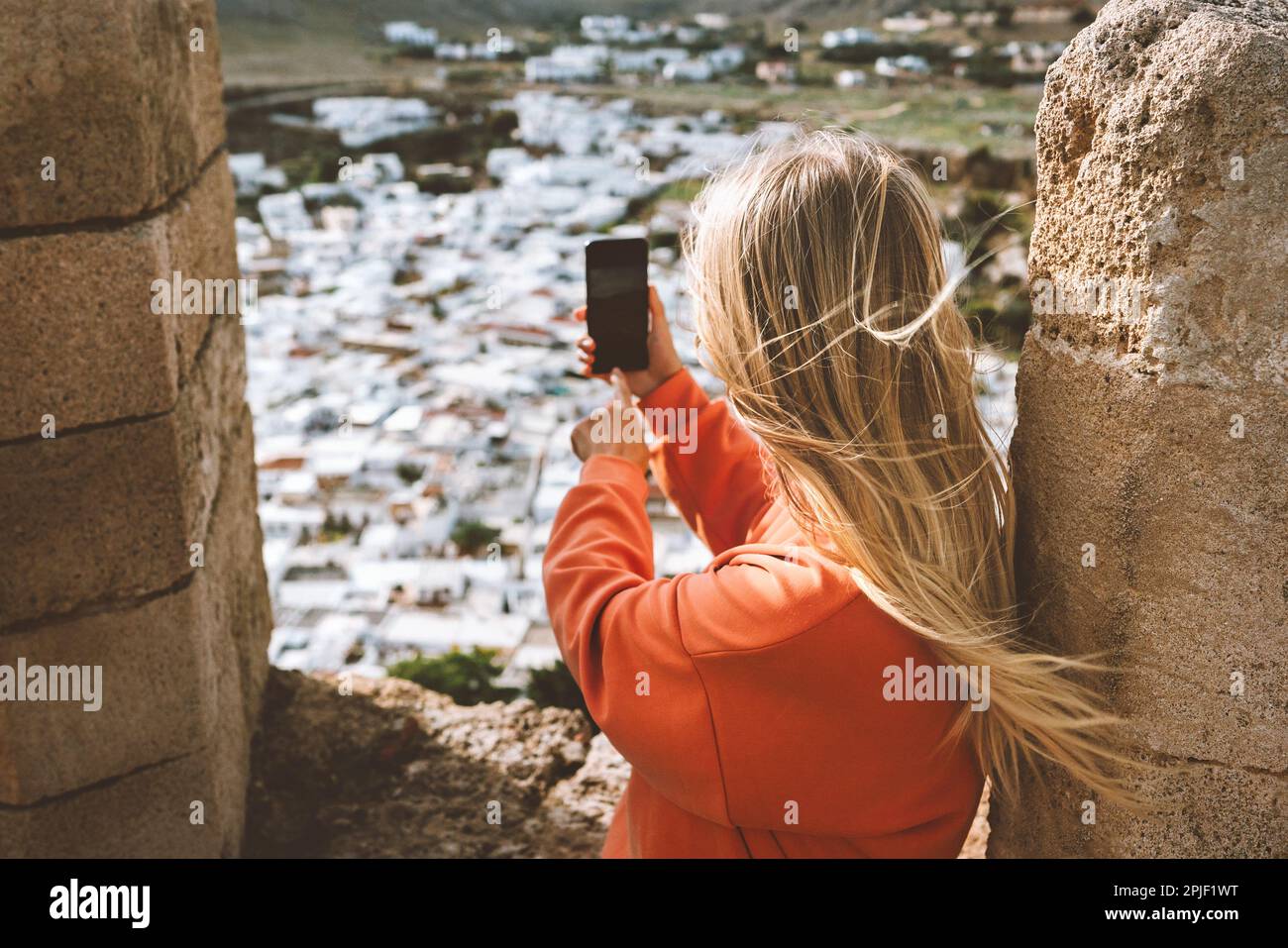 Viaggio blogger scattare foto a smartphone della città di Lindos a Rodi donna viaggiatore in Grecia visita aerea vista dall'Acropoli vacanze estive li Foto Stock