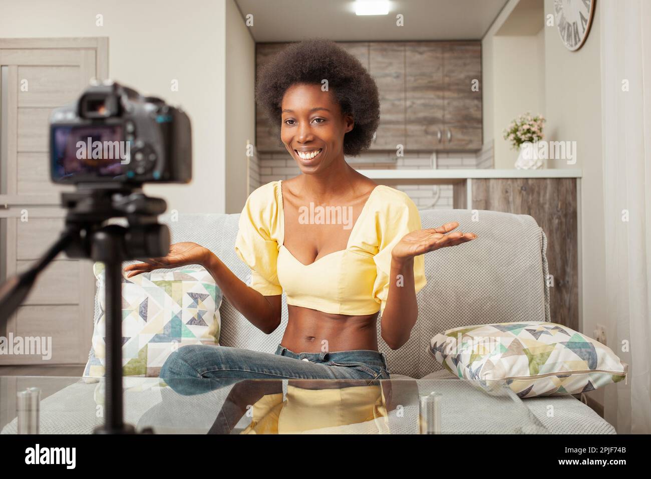 Una donna nera afro-americana blogger registra video sul canale, trasmissione online. Corsi, business. Sorridente, felice. Foto Stock
