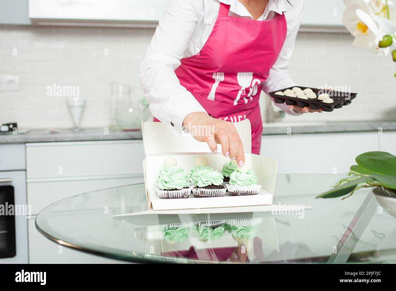 Il pasticciere decora cupcake, cucina fatta in casa, dolci. imprenditore, hobby domestico di affari Foto Stock