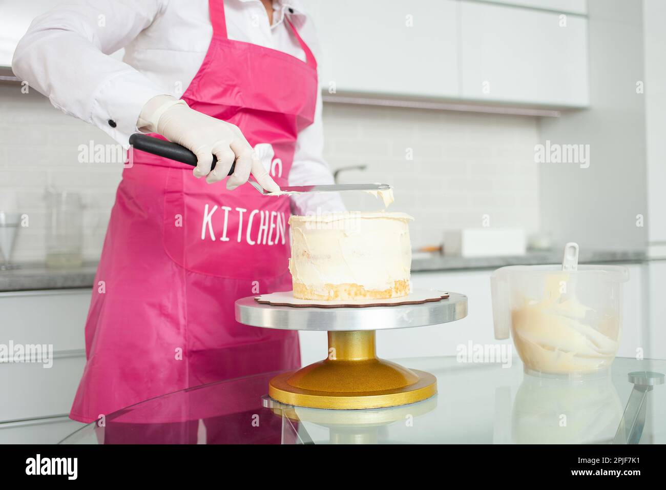 Un pasticcere gloved decora la torta con cioccolato bianco. Bella torta fatta in casa. grembiule Foto Stock