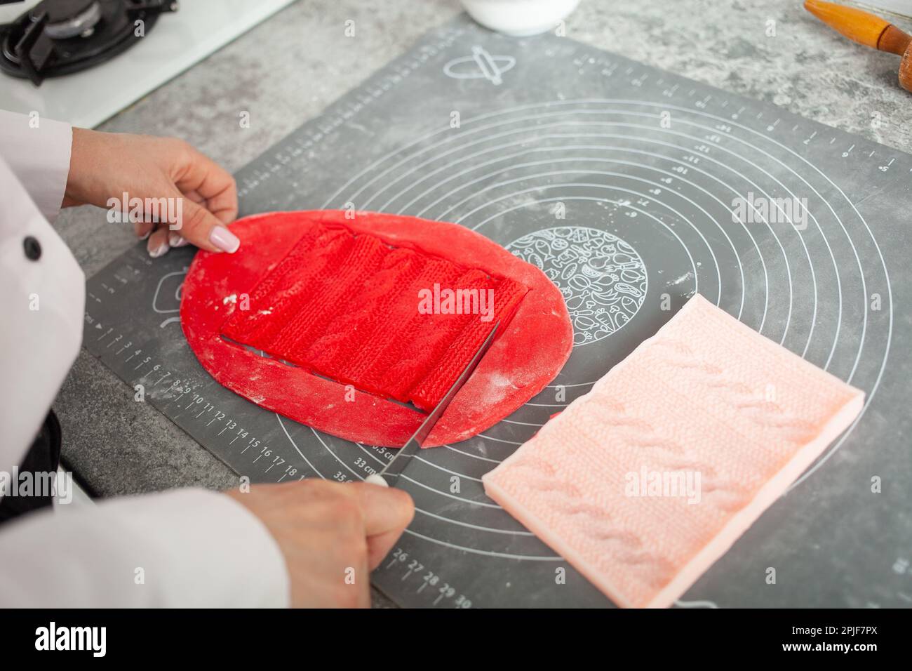 Il pasticciere fa il mastice per decorare la torta. Pasta elastica, deliziosi dolci, cottura. Produzione domestica, hobby, imprenditorialità. lavorato a maglia Foto Stock