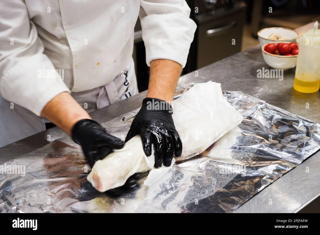 Lo chef prepara anche piatti di agnello. Il processo di cottura stinco di agnello chef maschio in una cucina professionale. Cucinare la carne in un ristorante caucasico Foto Stock